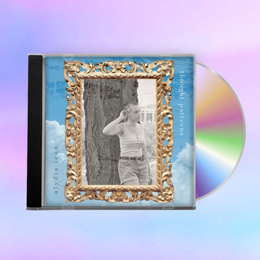 CD with the cover showing gold frame holding black and white photo on a cloud sky background. 